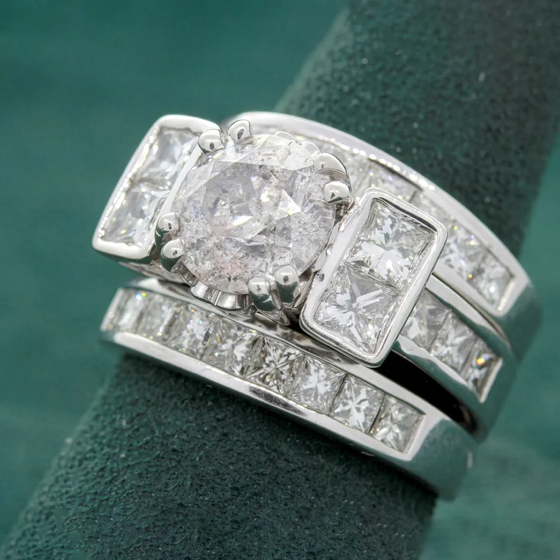 Elegant diamond engagement ring set featuring a round center stone and princess-cut side stones, displayed on a green background
