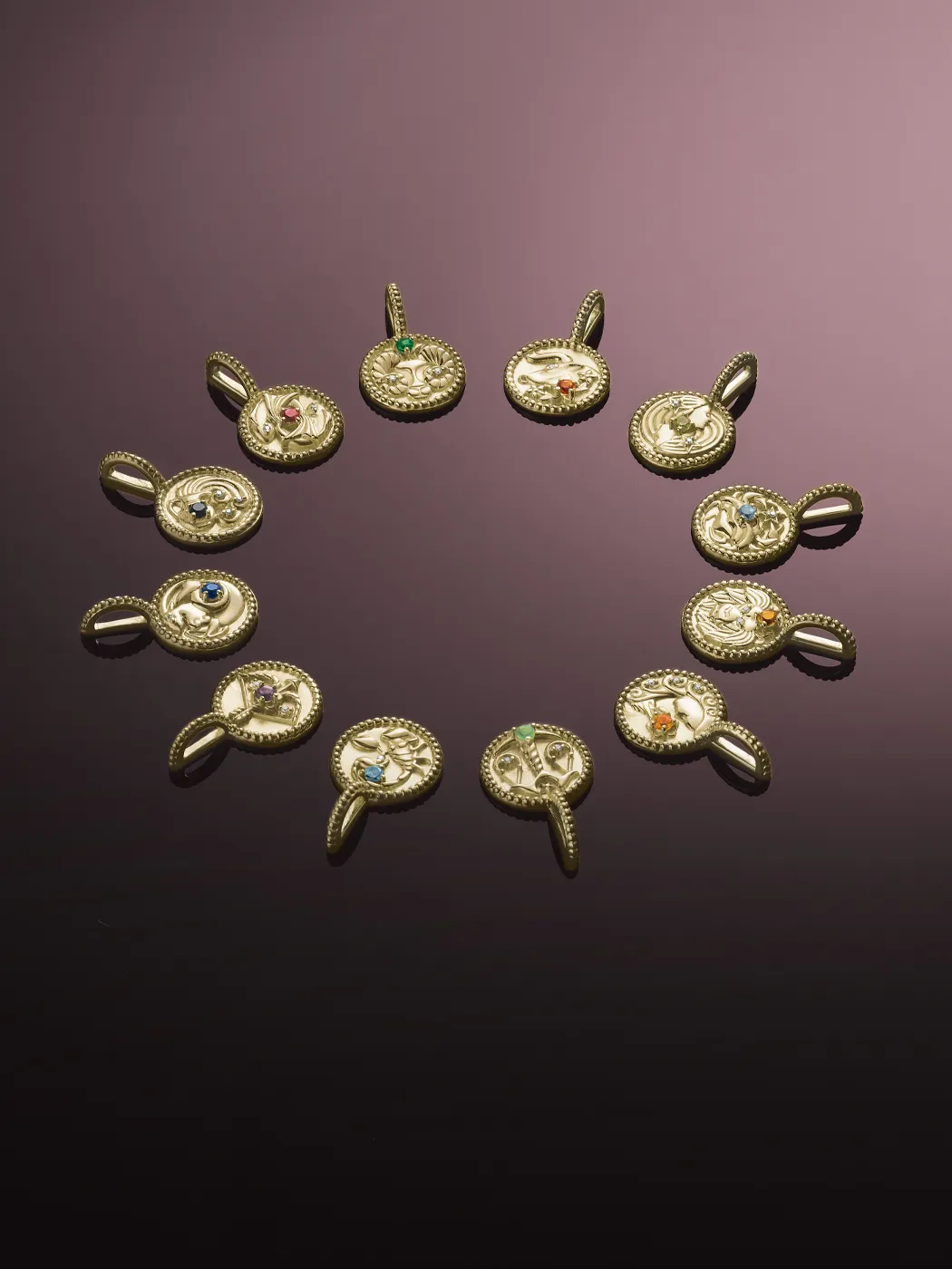 Gold pendants with colorful gemstones arranged in a circular pattern, showcasing intricate designs. Shop at Rich Custom Jewelry.