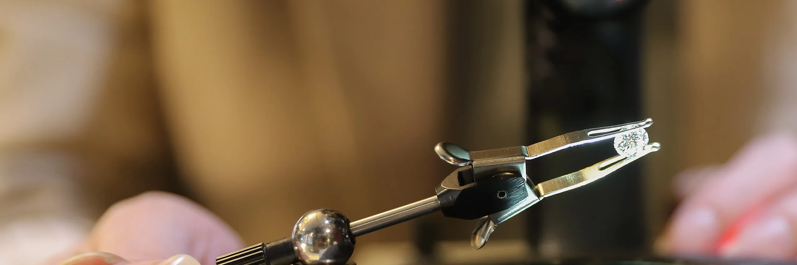Jeweler using a tool to hold a diamond for appraisal at Rich Custom Jewelry in Las Vegas. Click to learn more.