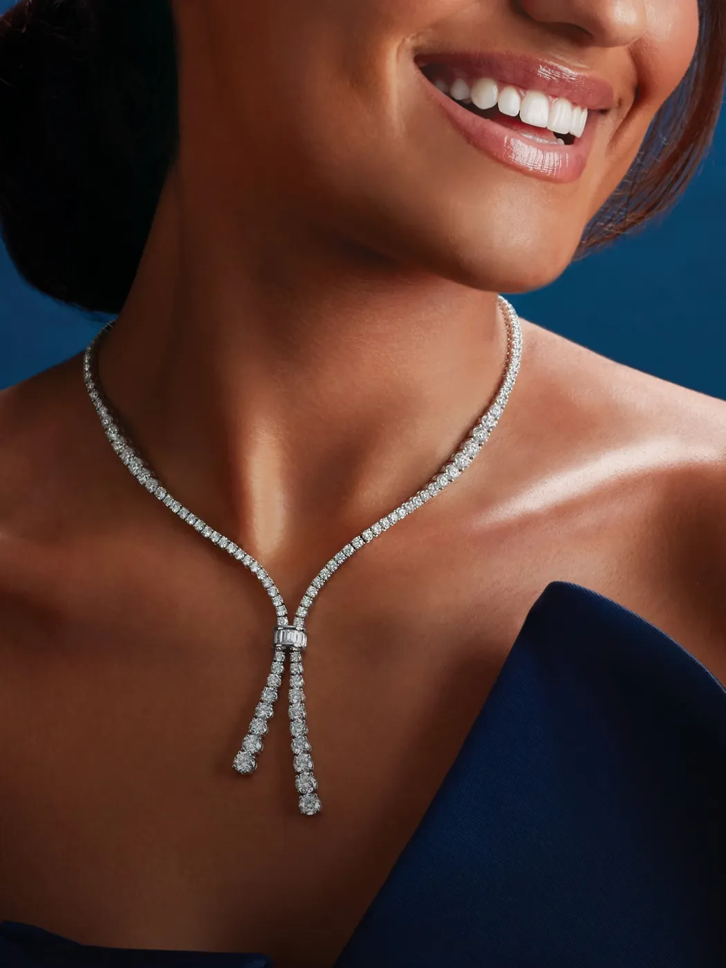Elegant woman wearing a diamond necklace, smiling, showcasing luxury jewelry.