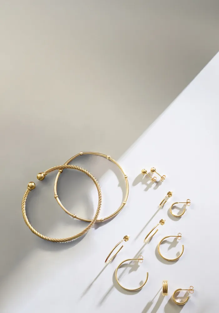 Gold earrings and hoops arranged artistically on a light background.
