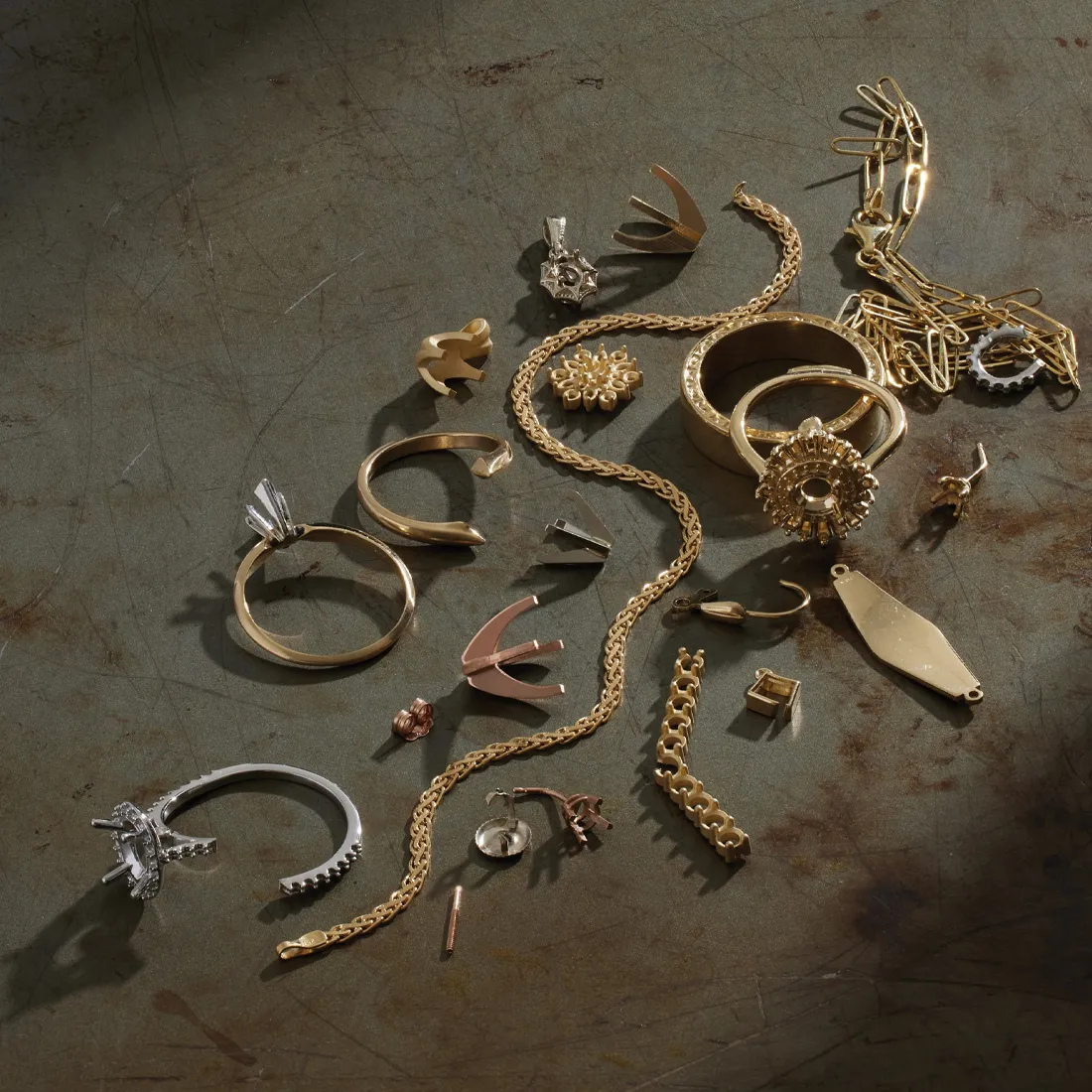 Assorted gold and silver jewelry pieces including rings, chains, and earrings on a textured surface.