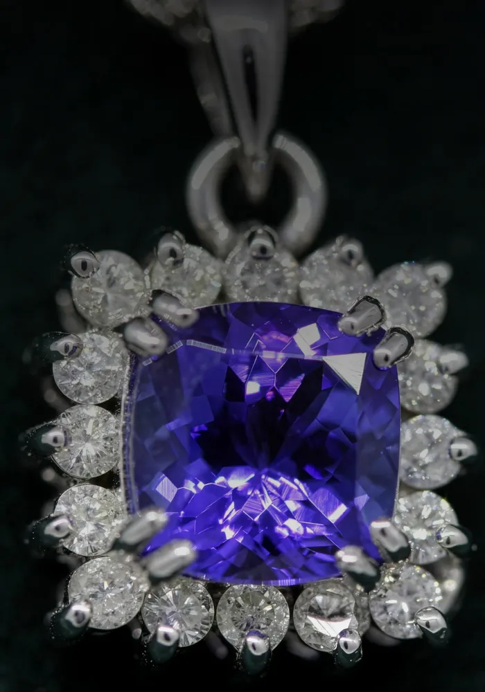 Purple gemstone pendant surrounded by diamonds on a dark background. 