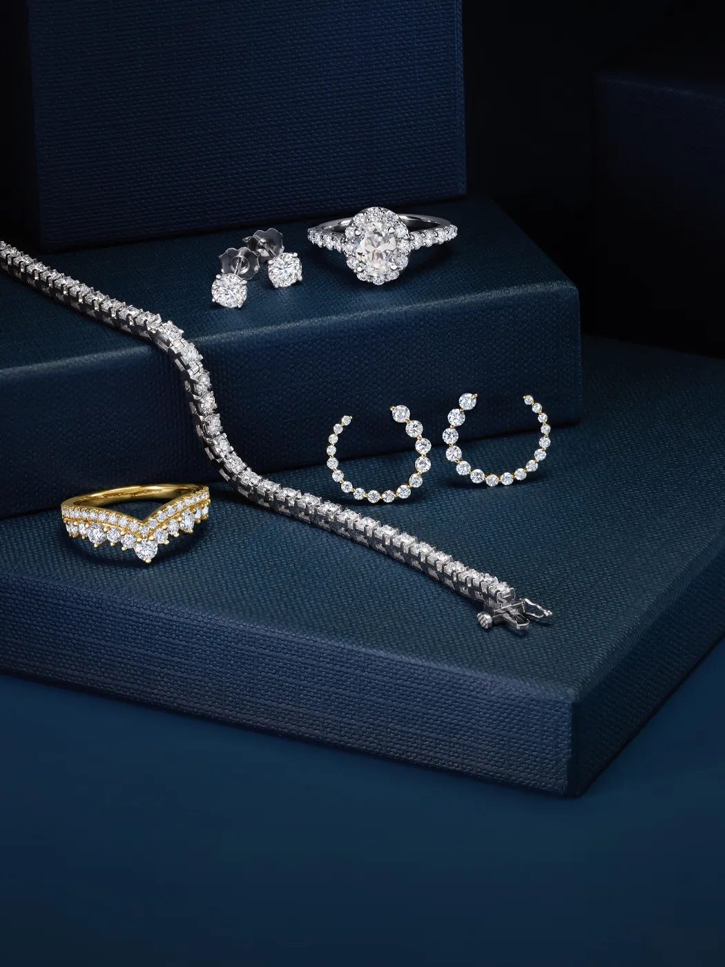 Elegant diamond jewelry display featuring rings, earrings, and a bracelet on dark blue boxes.
