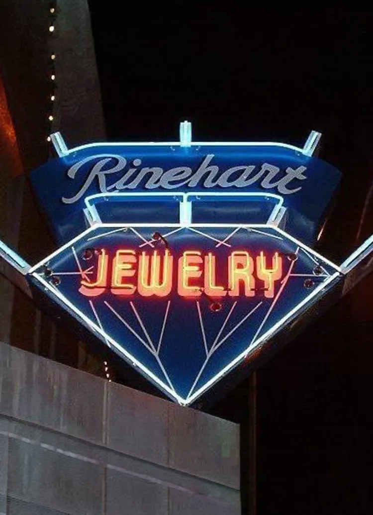 Neon sign for Rinehart Jewelry Co. in Nevada, shaped like a diamond with glowing letters.