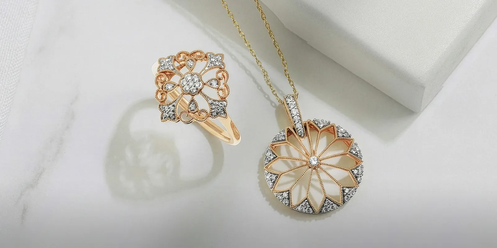 Rose gold ring and pendant with diamond accents on a white surface. Explore Lab Grown Diamond Jewelry.