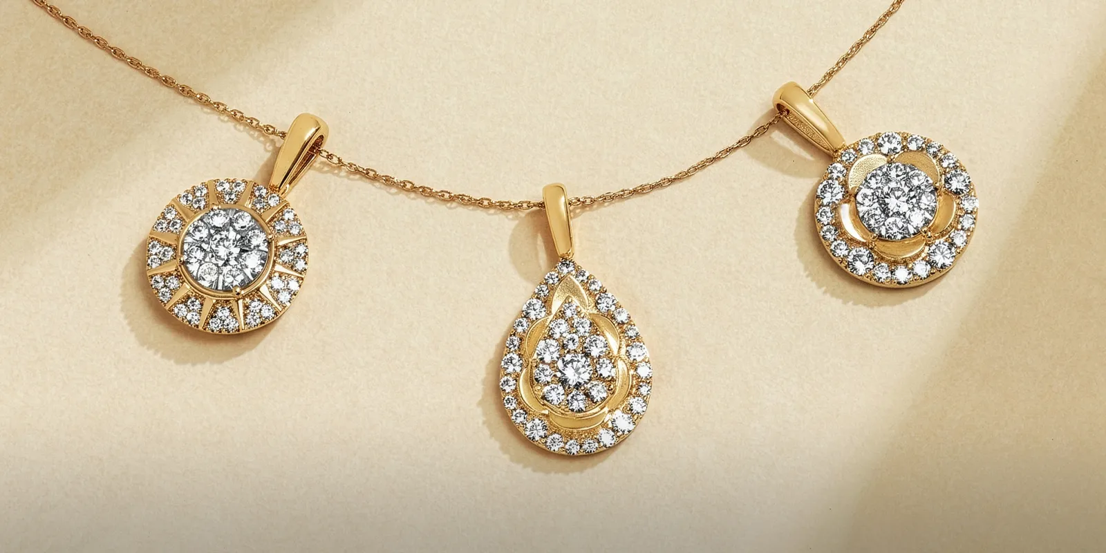 Three gold and diamond pendants on a chain. Click to explore Natural Diamond Jewelry.