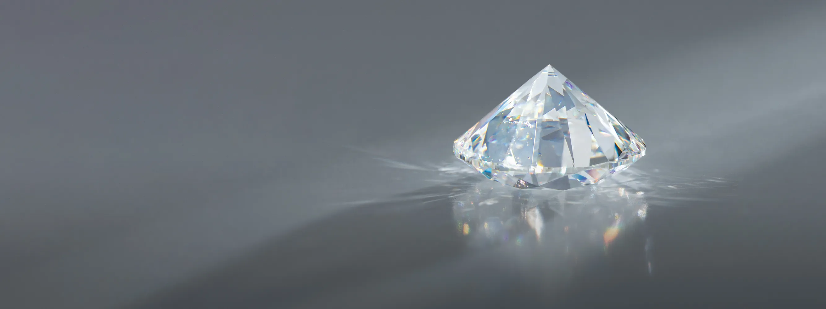 A sparkling diamond on a gray surface, reflecting light.