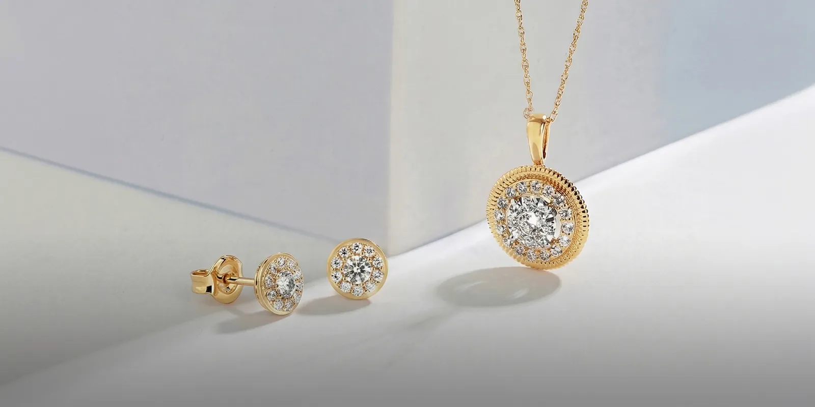 Gold necklace and earrings with diamond accents on a white surface.