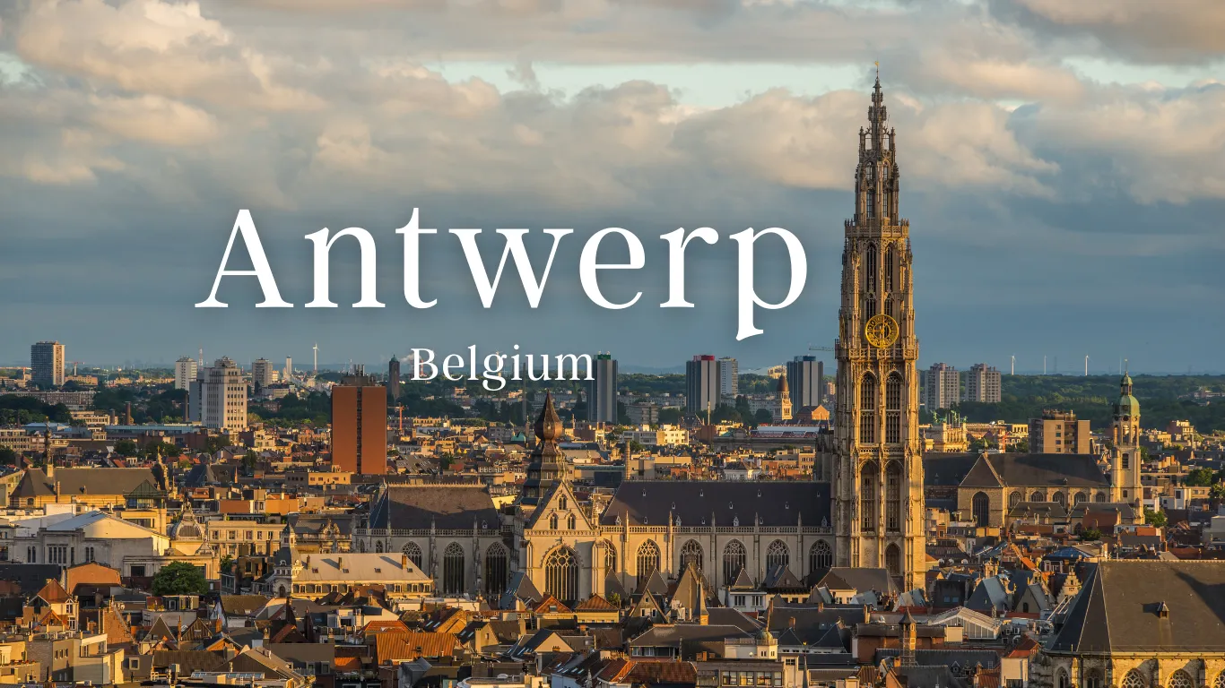 Skyline of Antwerp, Belgium with a prominent cathedral tower under a cloudy sky.