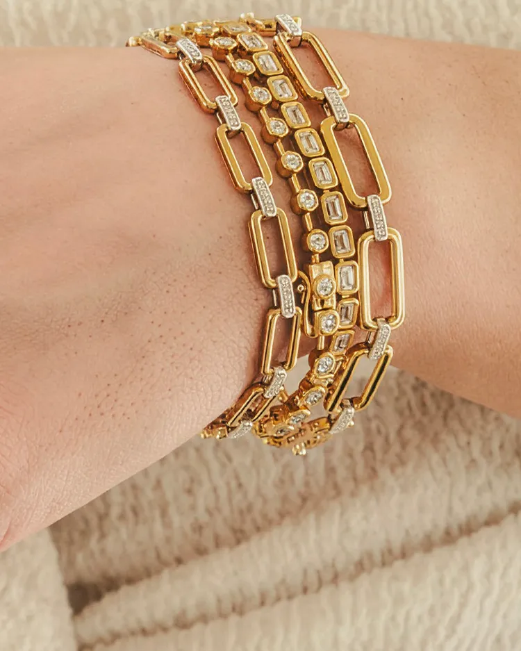 Gold layered bracelets with sparkling diamond accents on a wrist.
