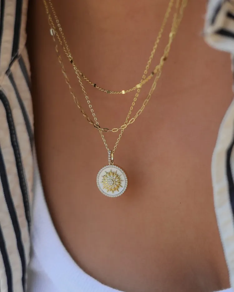 Gold layered necklace with a sun charm pendant, showcasing elegance and style.
