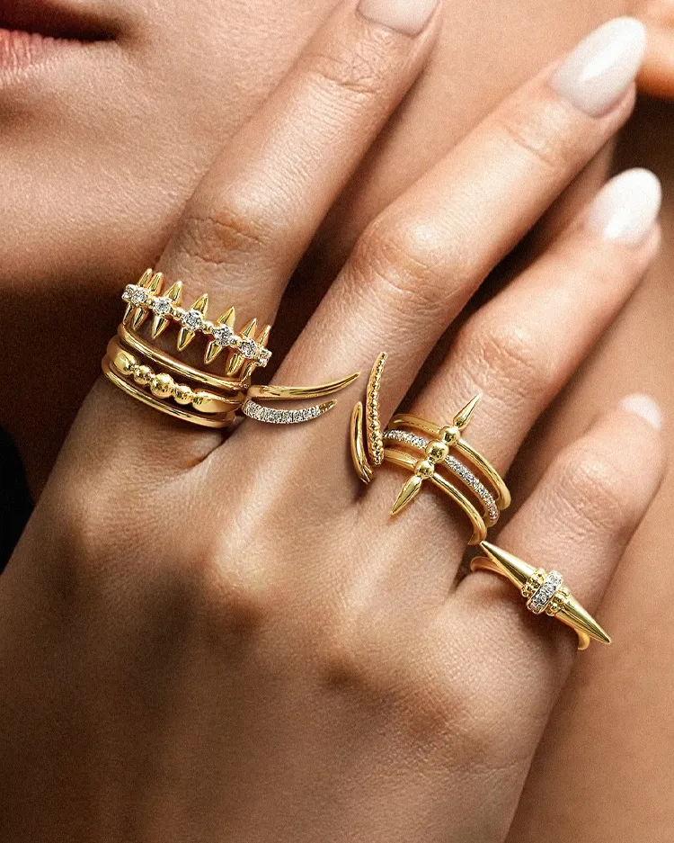 A hand adorned with multiple gold rings featuring spikes and diamonds.