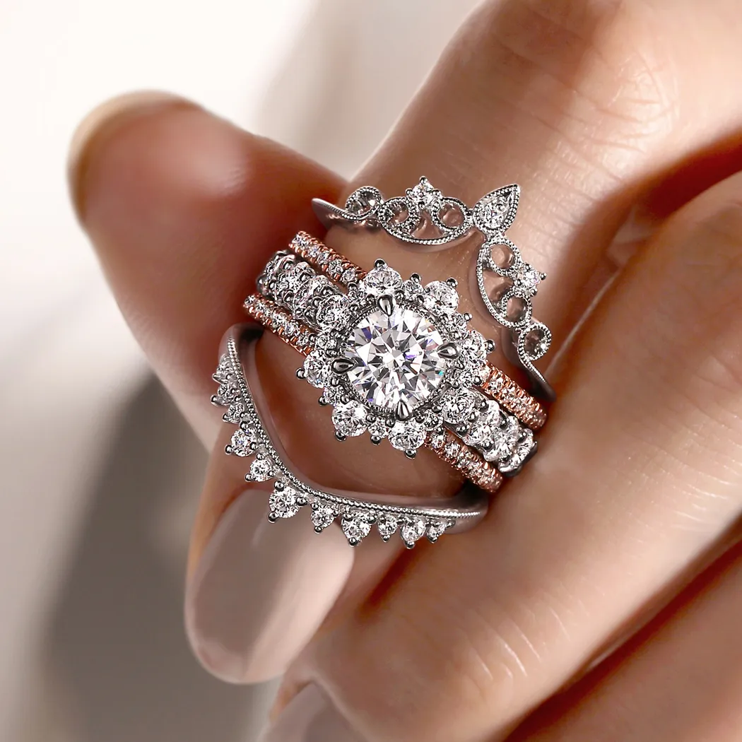 Elegant diamond engagement rings stacked on a hand, showcasing intricate designs and sparkling stones.