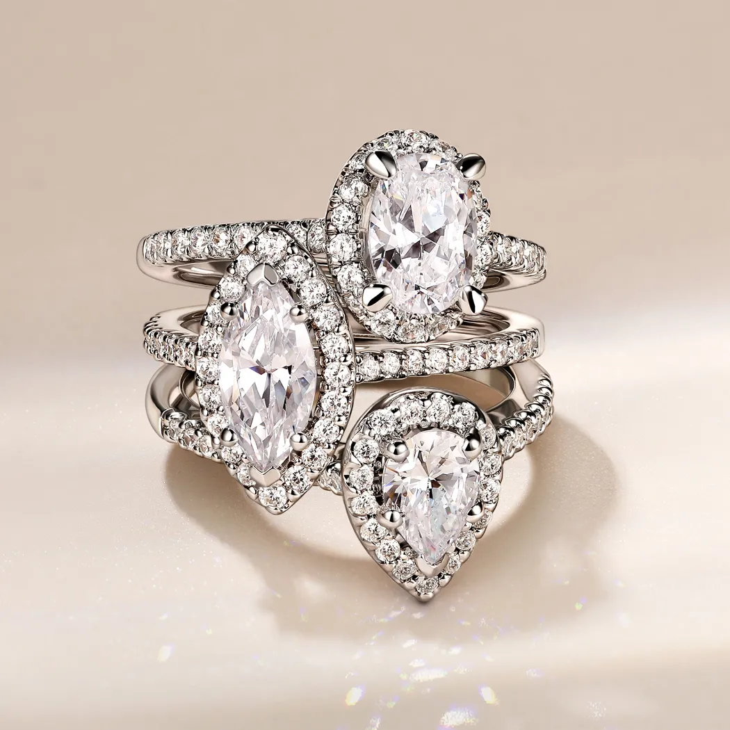 Three elegant diamond rings featuring pear and oval shapes, set in silver, showcasing intricate detailing.