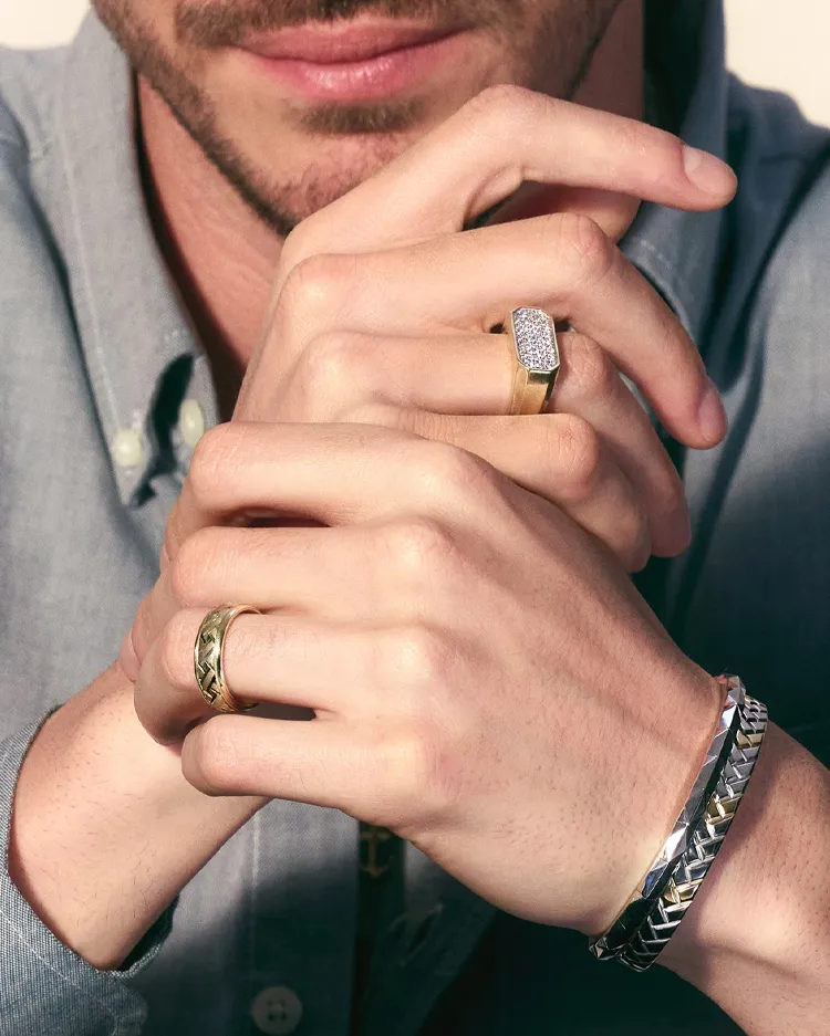Close-up of a man's hands showcasing gold and silver rings and a bracelet.