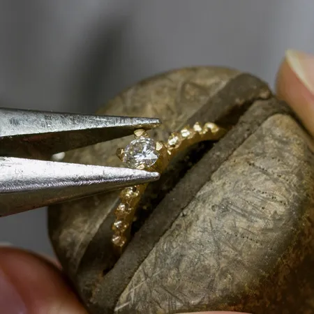Jeweler using pliers to hold a diamond ring, showcasing craftsmanship at Sather's Leading Jewelers in Fort Collins.