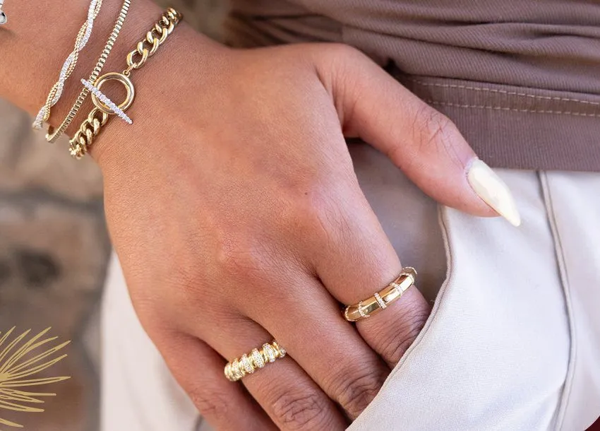 Layered gold and diamond bracelets with stacked gold rings