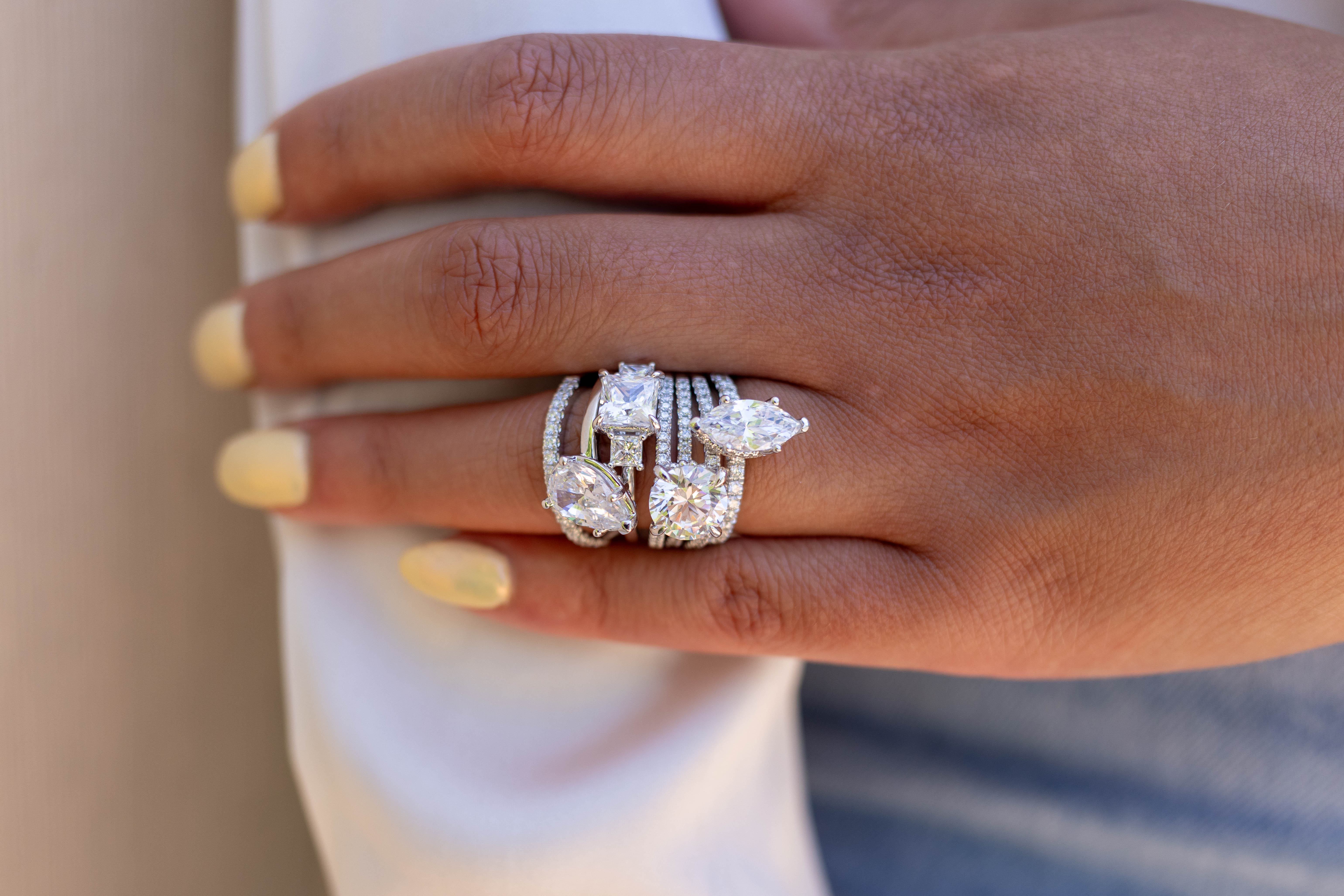 A hand displaying four elegant diamond rings. Click to learn more about bridal consultations at Sather's Leading Jewelers.