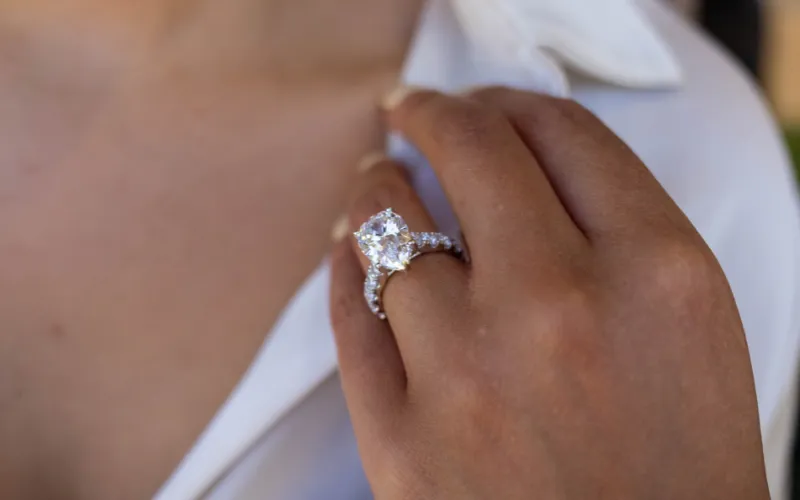 Close-up of a woman’s hand showcasing a stunning engagement ring with a large diamond and intricate band.