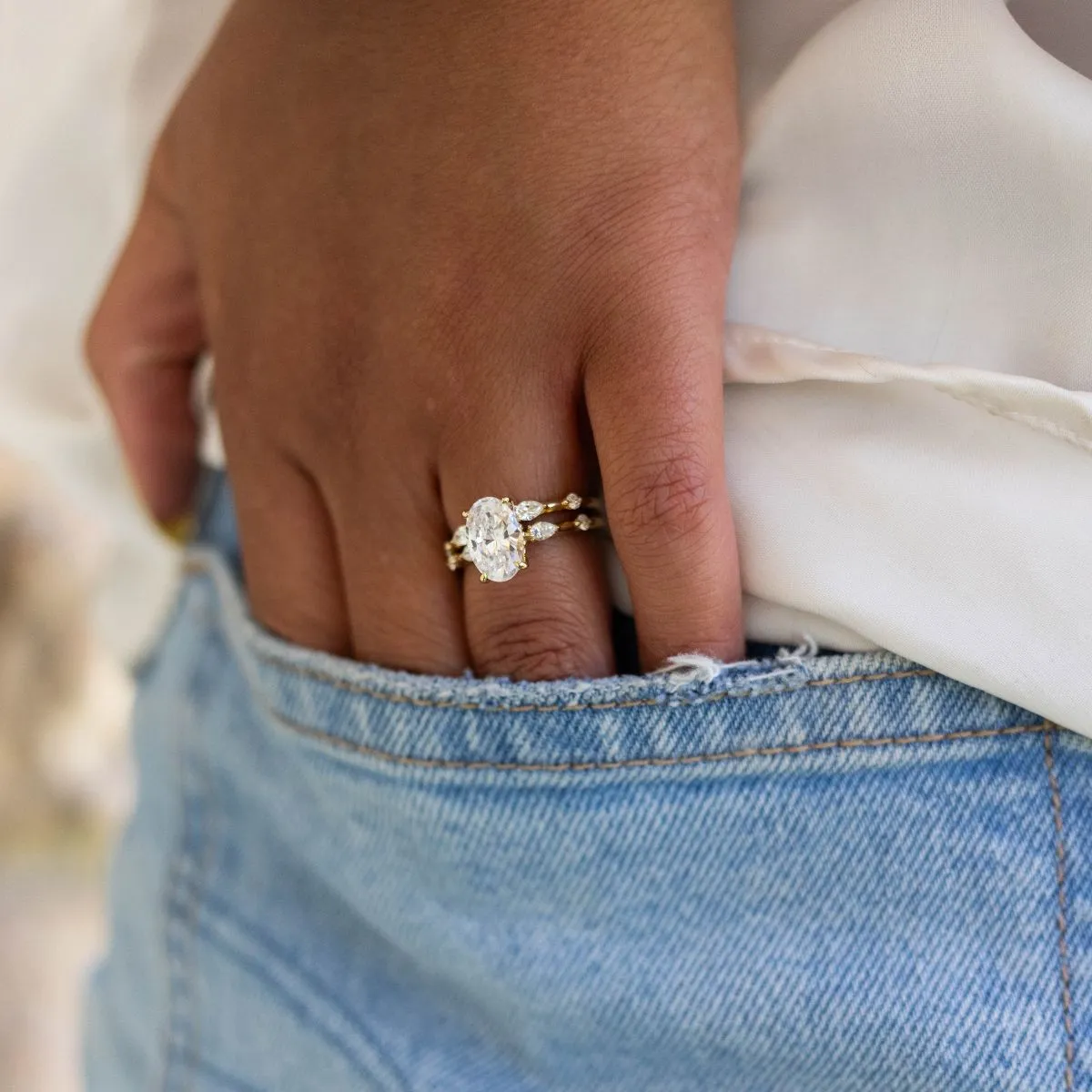 Elegant gold wedding band with an oval diamond, worn on a hand tucked into a denim pocket. Shop now at Sather's Leading Jewelers