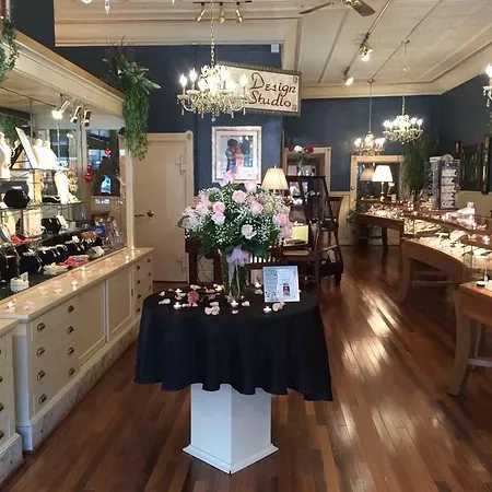 Elegant jewelry store interior with floral arrangement, showcasing fine jewelry and a design studio sign. Visit Sather's Leading