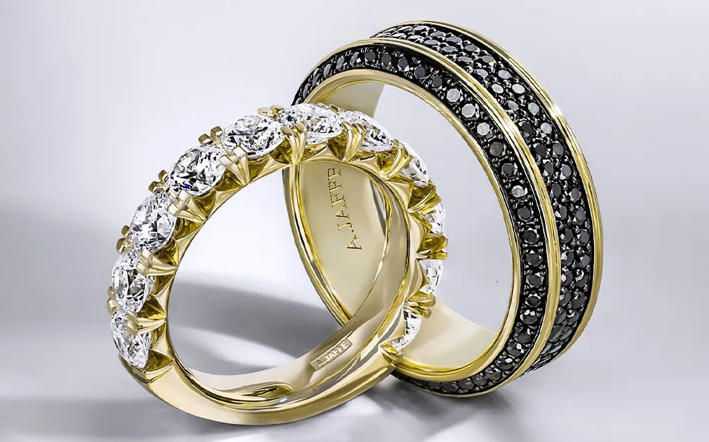 Two elegant rings: one with sparkling diamonds in gold, the other with black stones, showcasing fine jewelry craftsmanship.