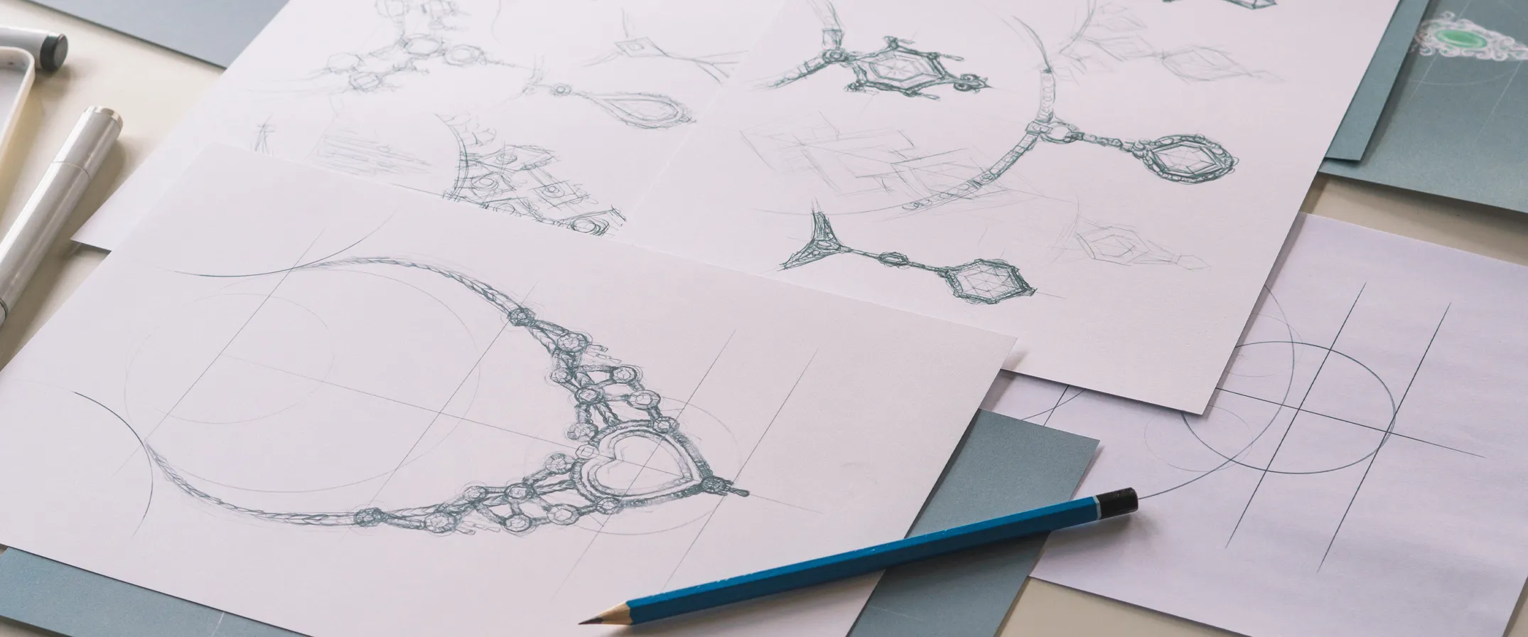 Sketches of intricate jewelry designs on paper with a blue pencil, showcasing custom jewelry concepts.