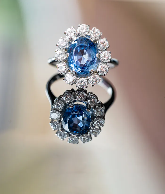 Elegant blue gemstone ring surrounded by sparkling diamonds, reflecting beautifully.