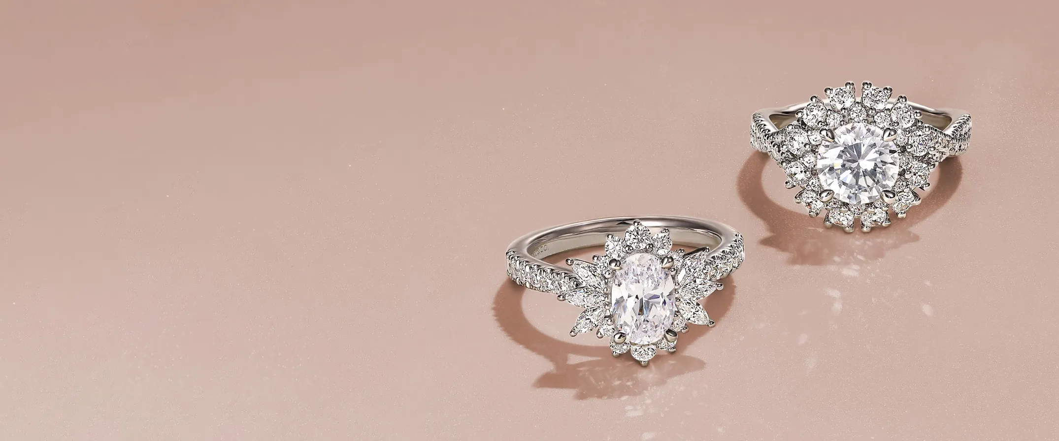 Two elegant diamond rings on a soft pink background, showcasing modern design. Click to shop Gabriel & Co. jewelry.