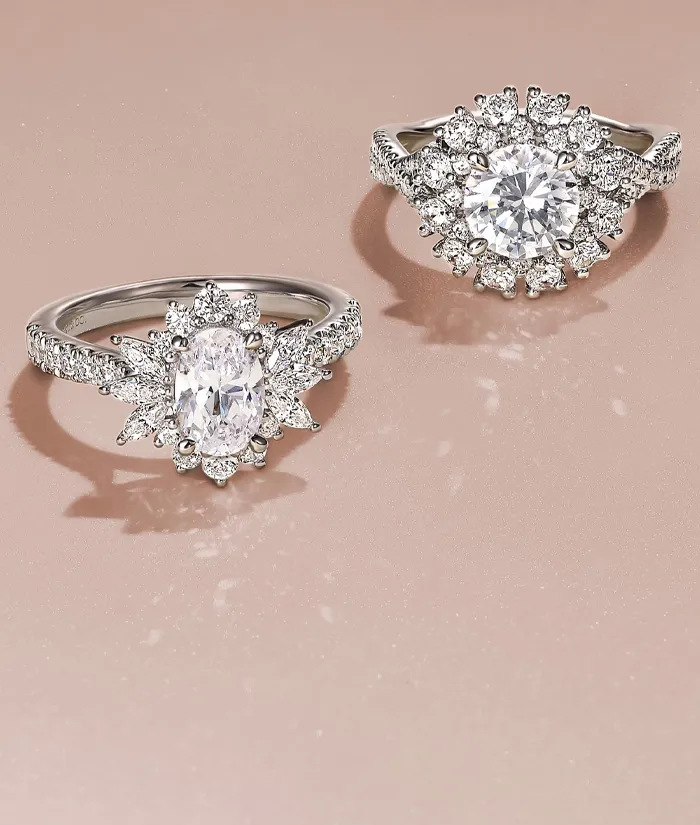 Two elegant diamond rings on a soft pink background, showcasing modern design. Click to shop Gabriel & Co. jewelry.