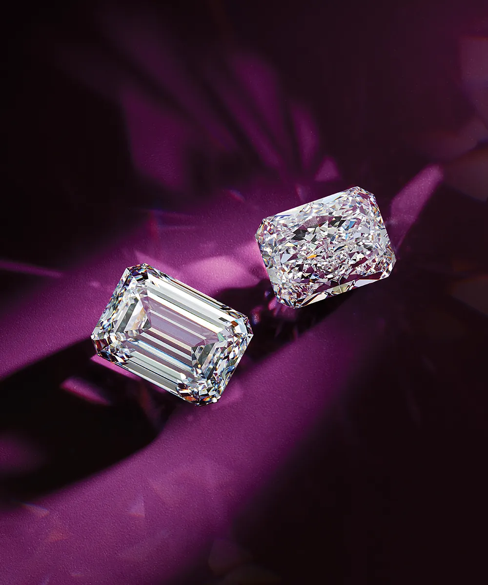 Two radiant-cut diamonds on a purple background, casting shadows.