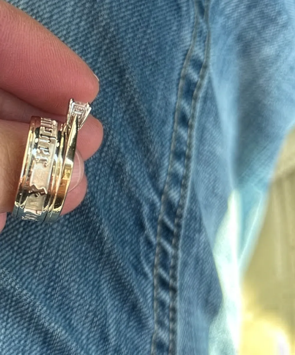 A hand holding a stack of rings against a denim background.