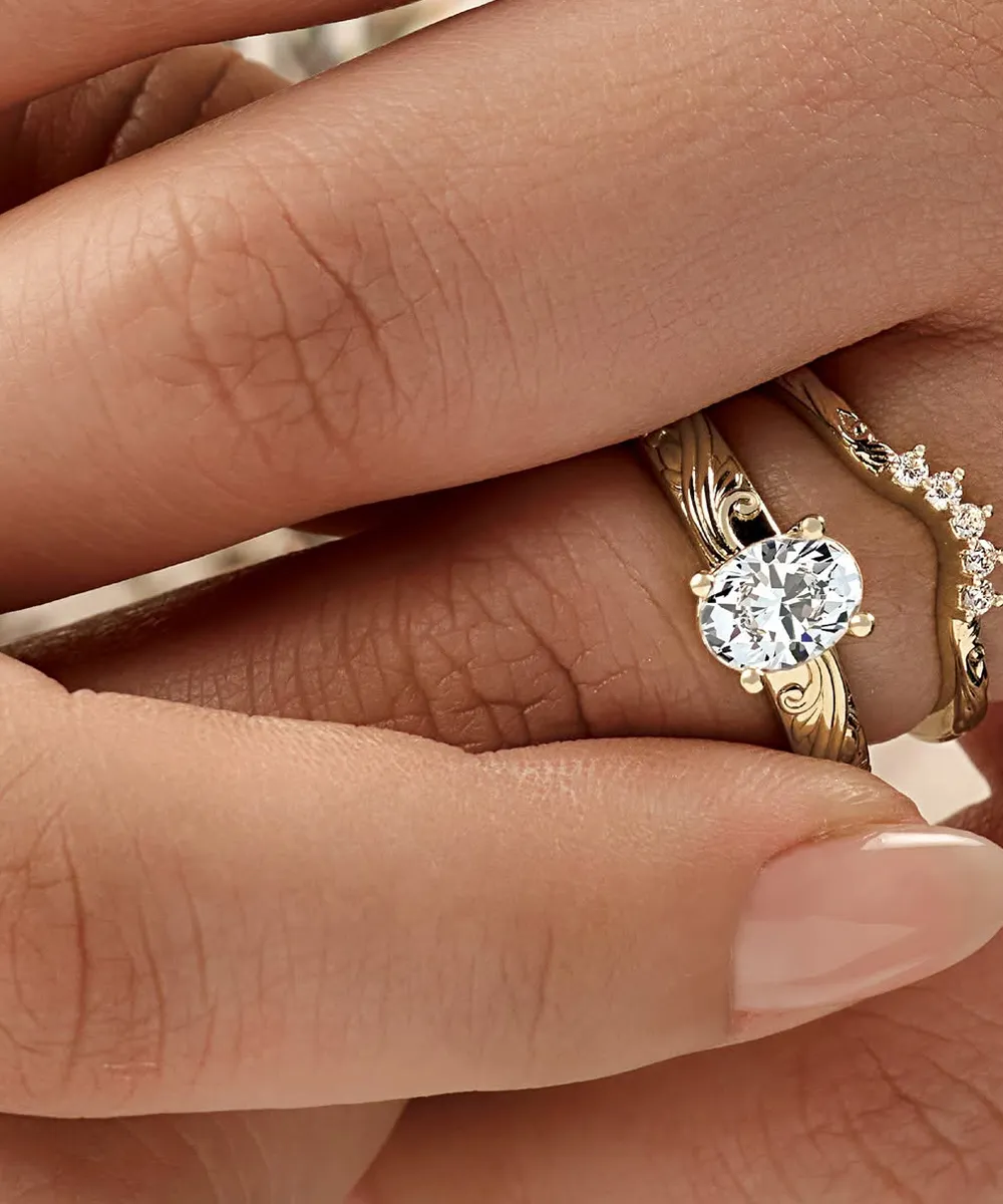 A hand wearing two gold rings, one with a large oval diamond and the other with small diamonds.