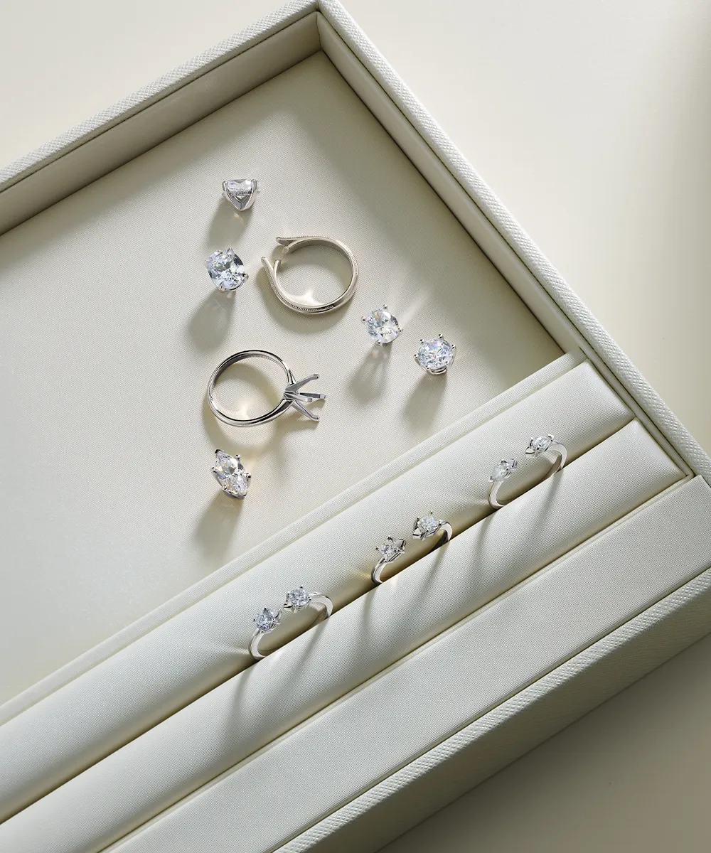A jewelry box displaying diamond rings and loose stones on a light background.