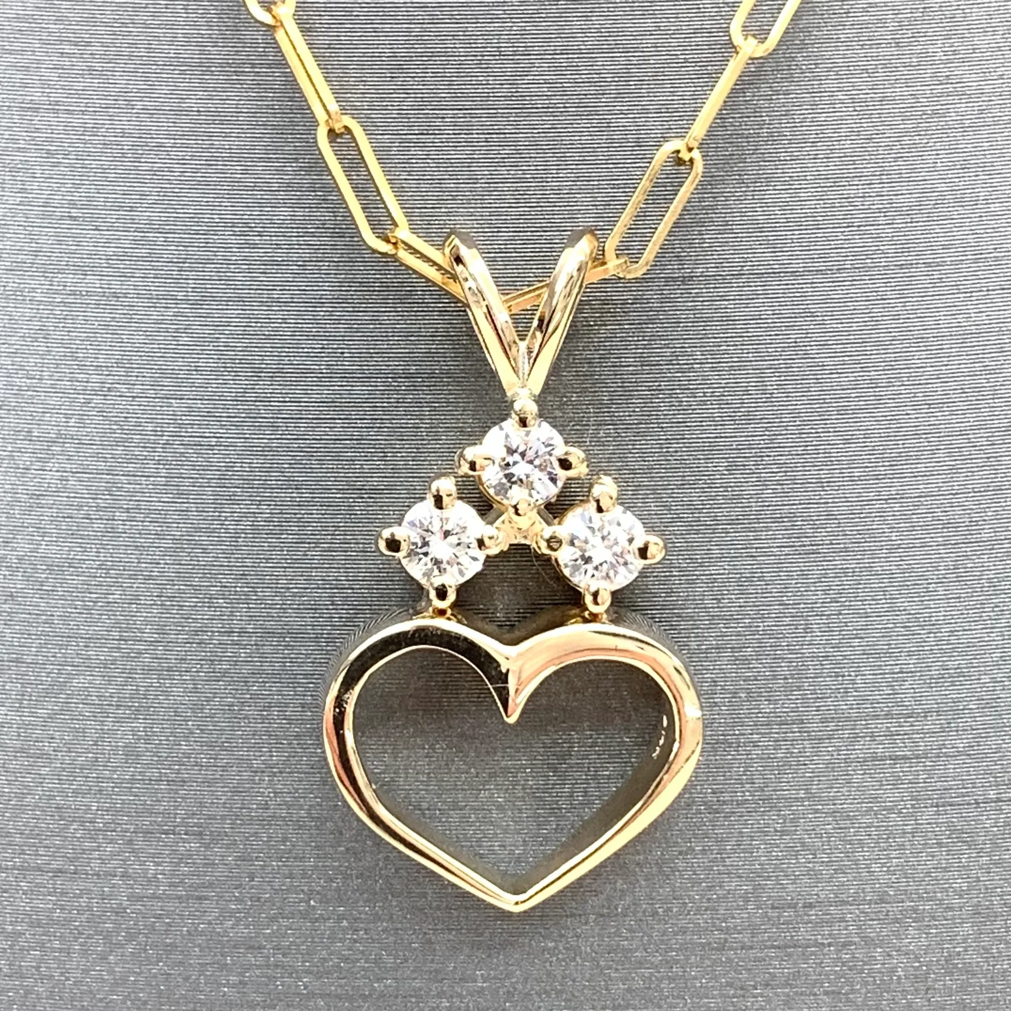 Gold heart pendant with three diamonds on a chain.