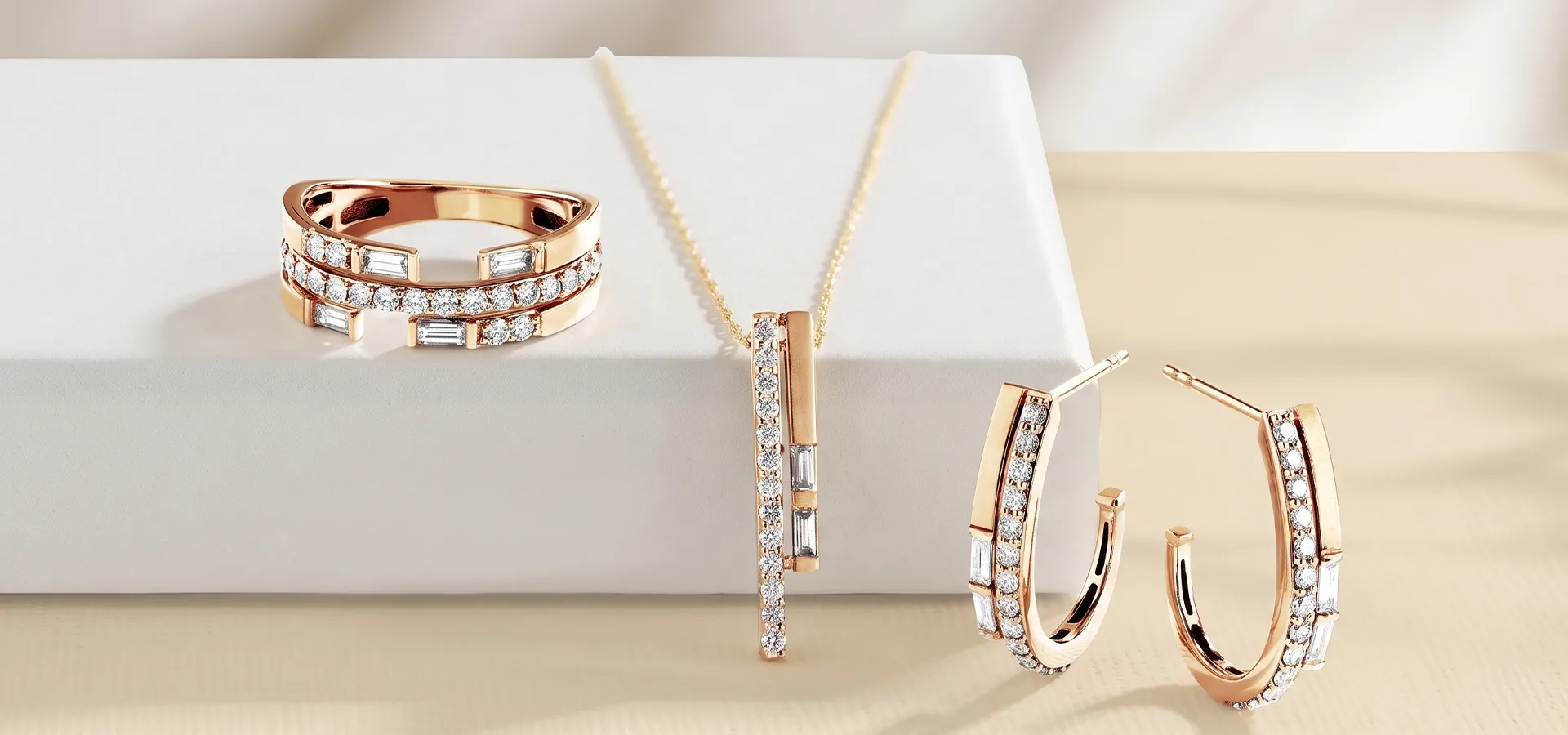A set of rose gold jewelry with diamonds, including a ring, necklace, and earrings, displayed on a white surface.