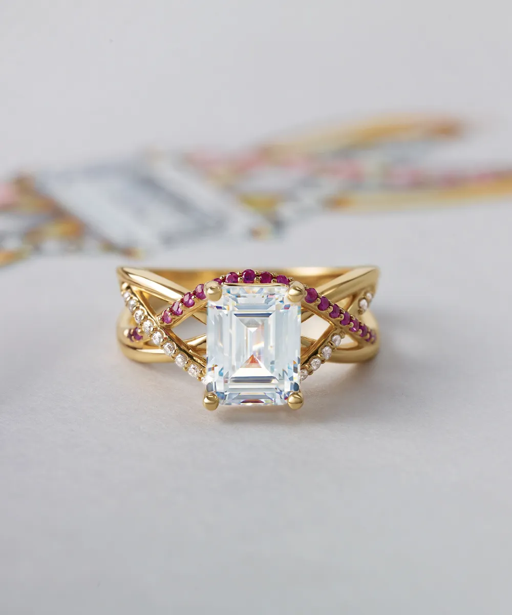 A gold ring with a large rectangular gemstone, accented by red and white stones on a crisscross band.