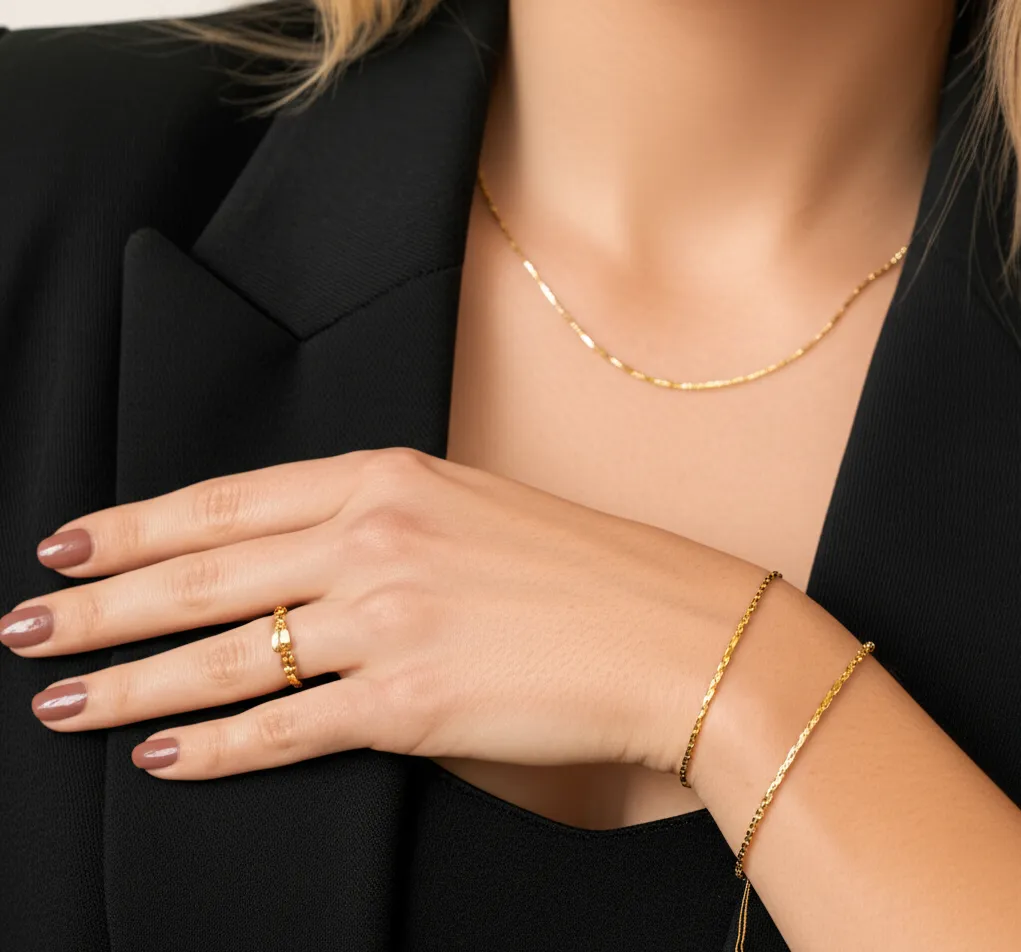 Elegant hand adorned with gold and silver bracelets, featuring a stunning engagement ring, surrounded by pink flowers. Shop Here