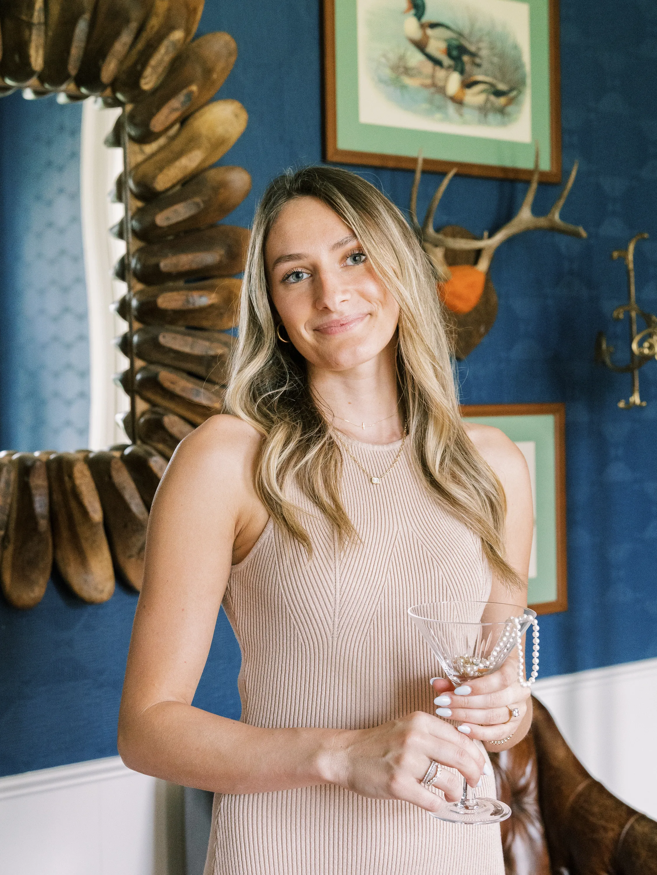 Jaci Spies, owner of Segner's Jewelers, smiles holding a martini glass adorned with pearls in a stylish setting.