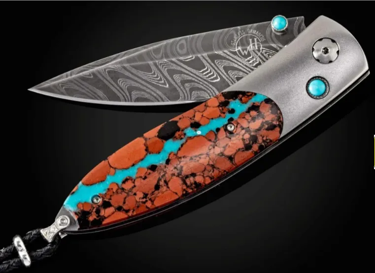 Marbled Turquoise William Henry Knife The Monarch 'Lava Lake' features a frame in titanium, inlaid with vein turquoise and lava rock. The blade is hand-forged 'Boomerang' damascus by Chad Nichols. The one-hand button lock and the thumb stud are set with turquoise cabochons. Segners Jewelers Fredericksburg, TX