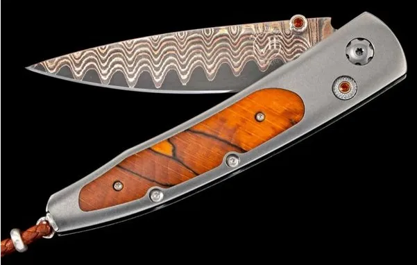 Beachwood William Henry Knife The Lancet 'Beech' features a light and resilient frame in aerospace grade titanium, inlaid with orange spalted beechwood. The blade is in William Henry's signature 'Copper Wave' damascus steel with an extra sharp core in VG-5 steel; the one-hand button l Segners Jewelers Fredericksburg, TX