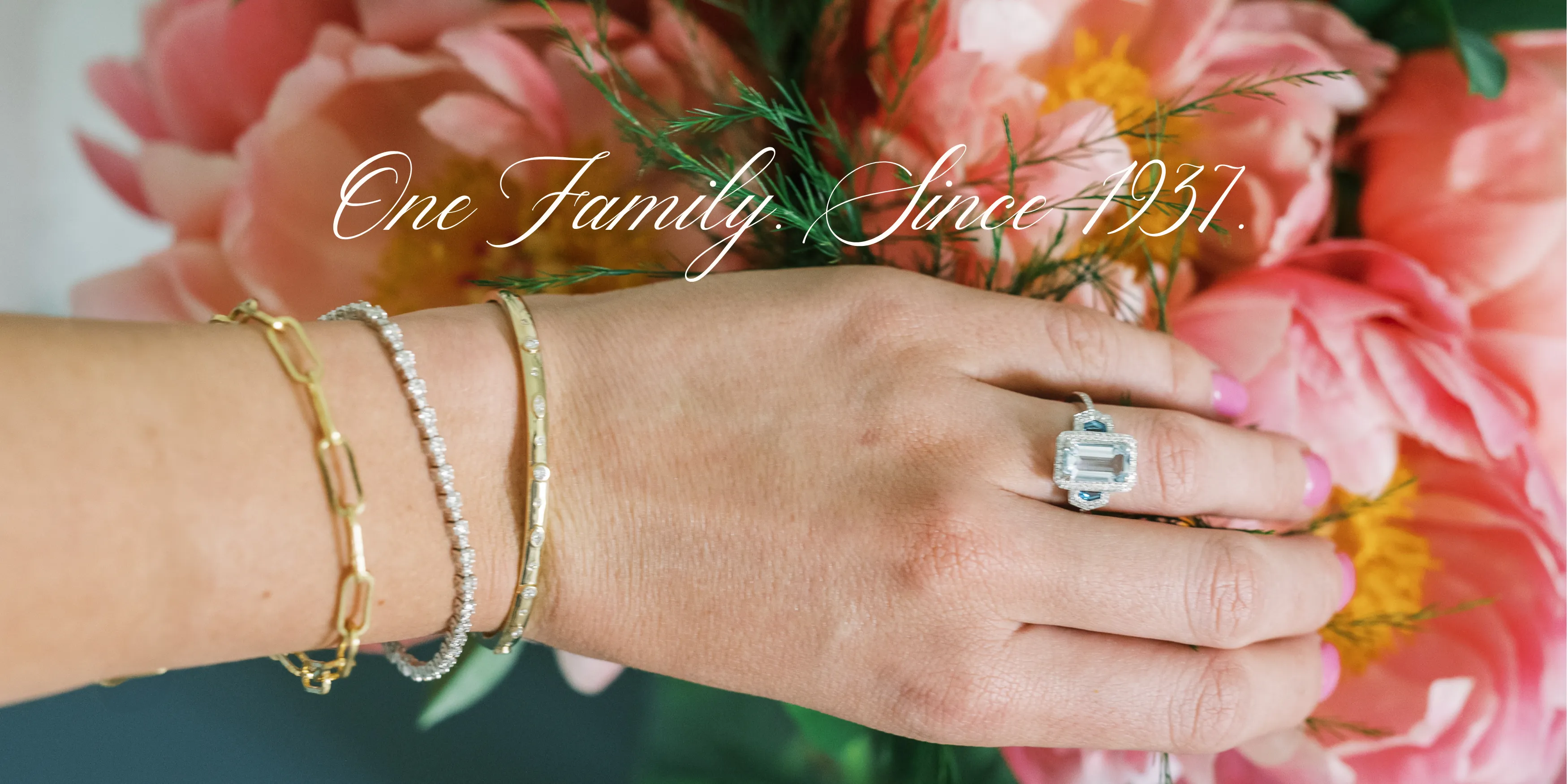 Elegant hand adorned with bracelets and a ring, surrounded by pink peonies. 