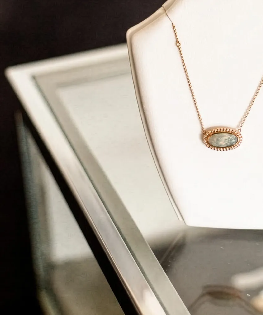 Elegant necklace with oval pendant displayed on a white stand at Stephen's Fine Jewelry, Leawood.