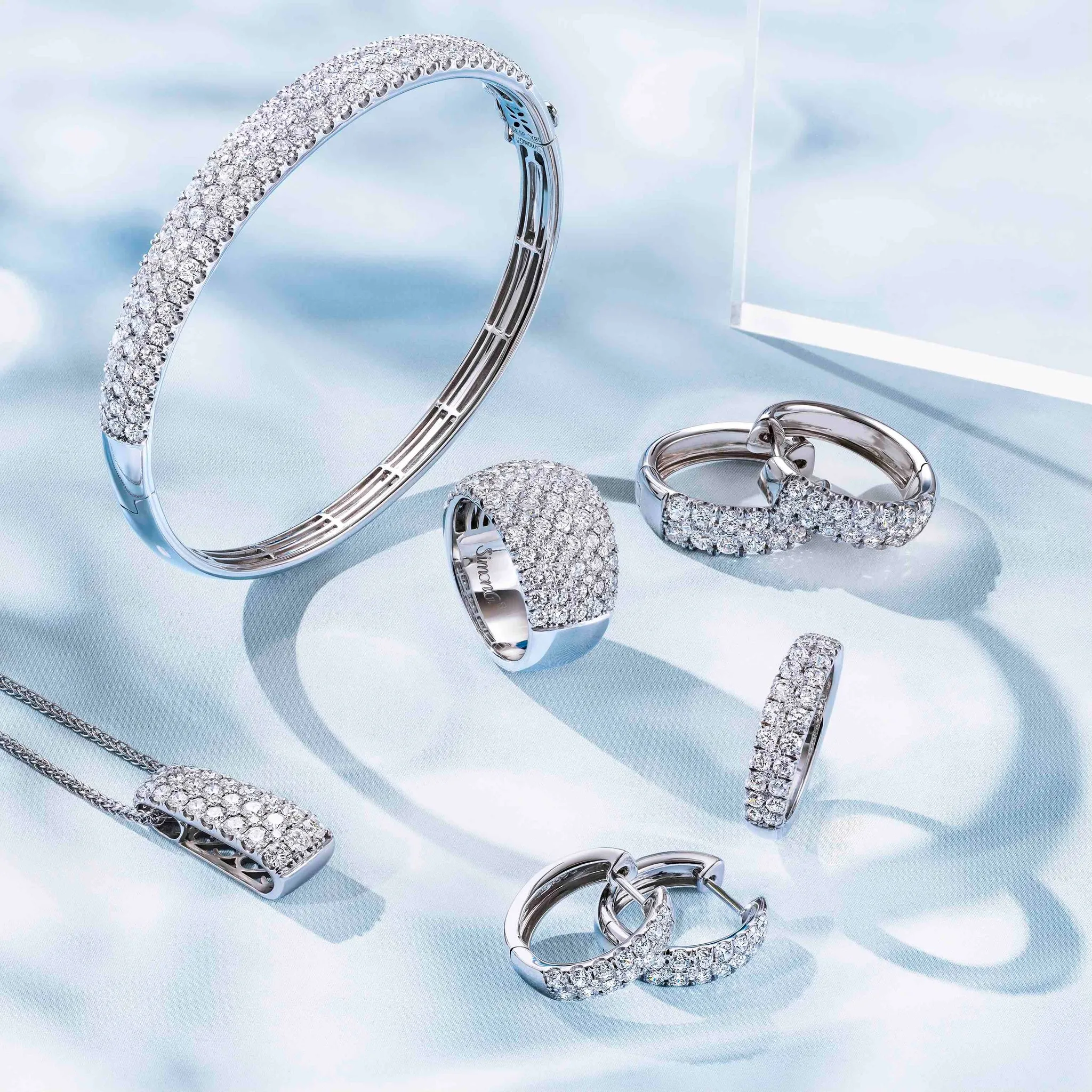 A hand holding a sparkling silver bracelet with intricate designs, showcasing fine jewelry craftsmanship.