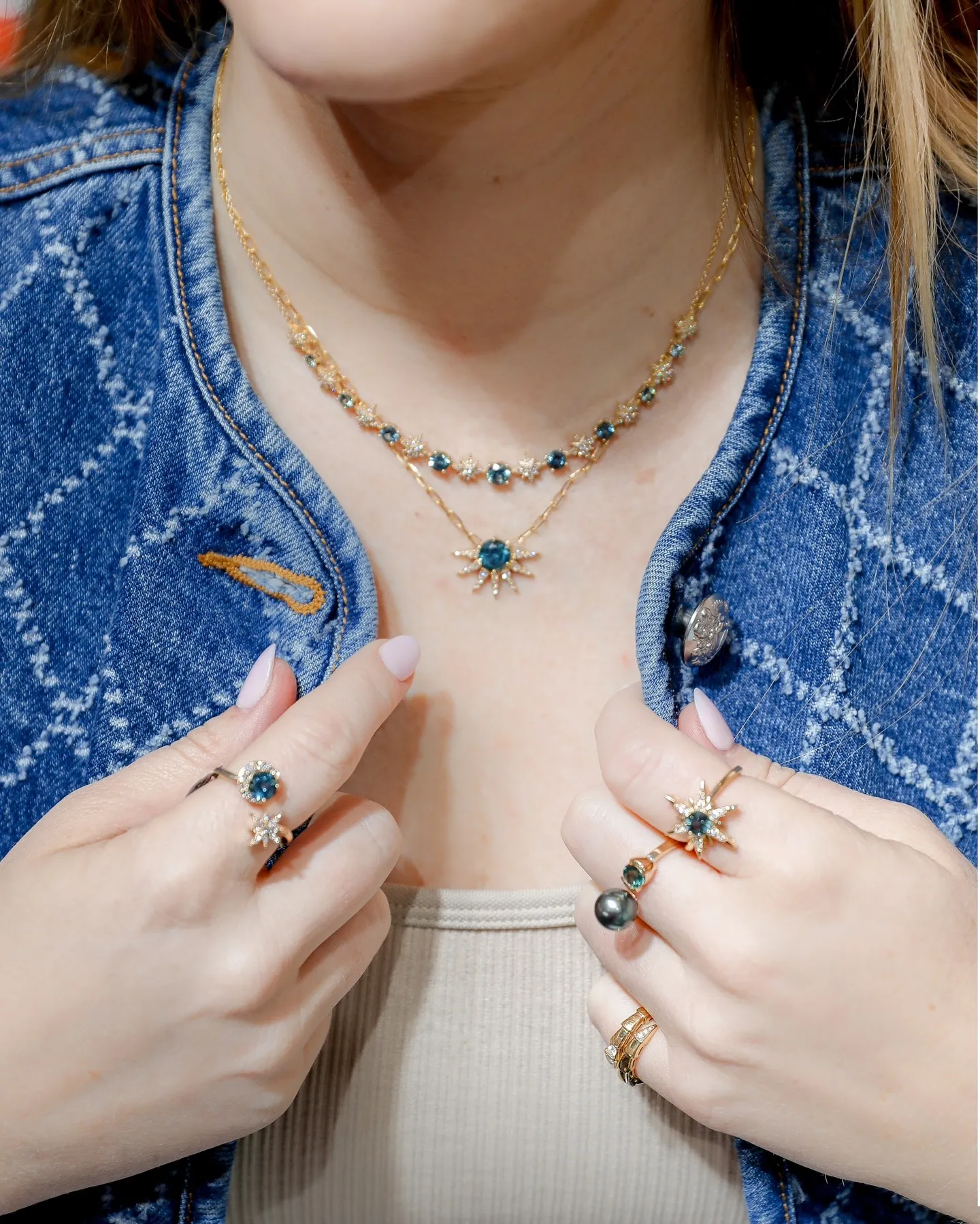 A woman with long dark hair wearing elegant earrings and rings, showcasing fine jewelry from Sterling Jewelers.