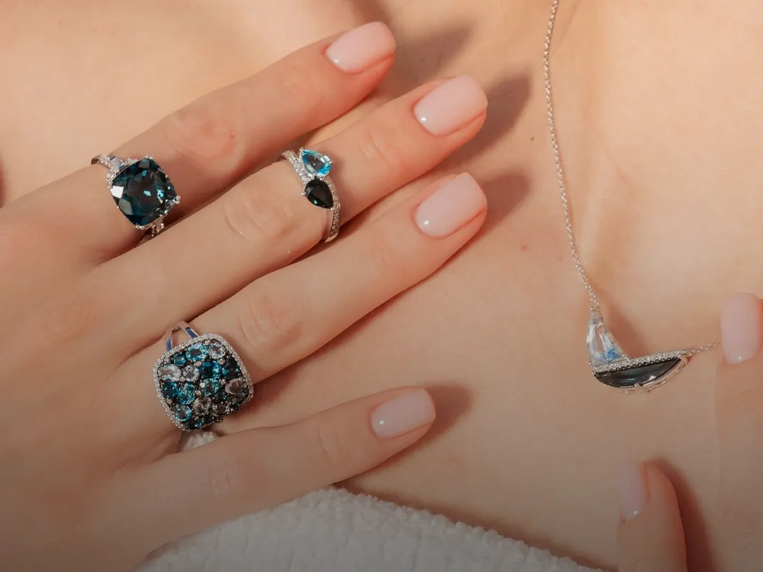 Elegant blue gemstone jewelry display featuring rings and a necklace.