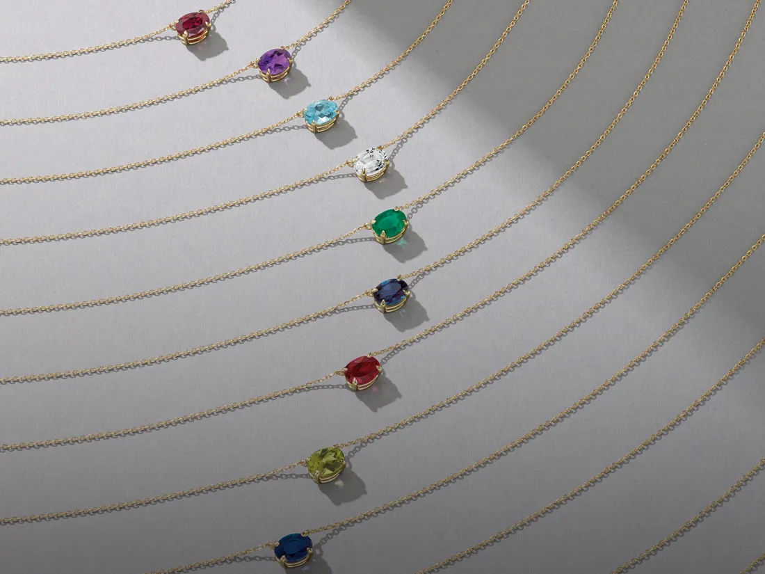Colorful birthstone necklaces displayed on gold chains, promoting birthstone jewelry.