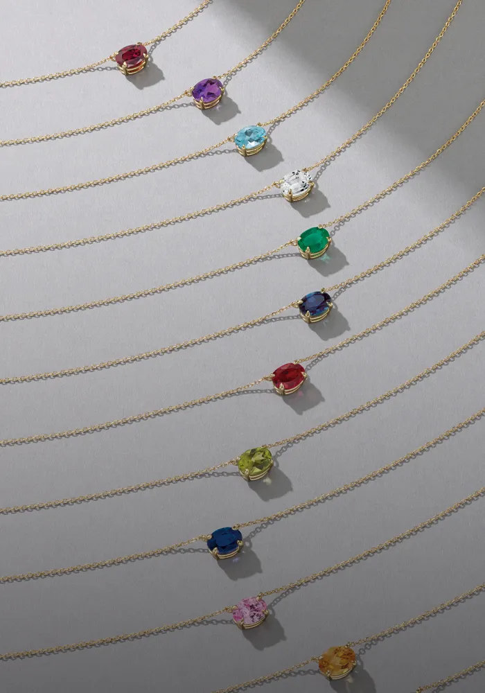 Colorful birthstone necklaces displayed on gold chains, promoting birthstone jewelry.