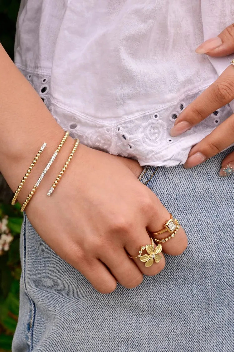 Close-up of a hand wearing gold bracelets and rings, showcasing elegant jewelry.